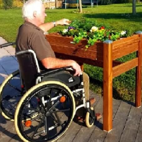 personne âgée en fauteuil roulant qui jardine dans un jardin hors-sol